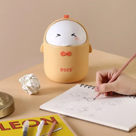 Mini desktop trash can with a duck design, perfect for storing small waste on a desk, shown next to a sketchpad and pencil