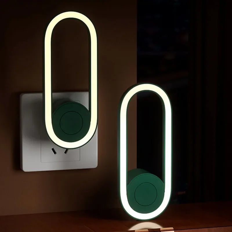 Modern ultrasonic mosquito repellent night light plugged into a wall socket, emitting a soft glow and featuring a sleek oval design.